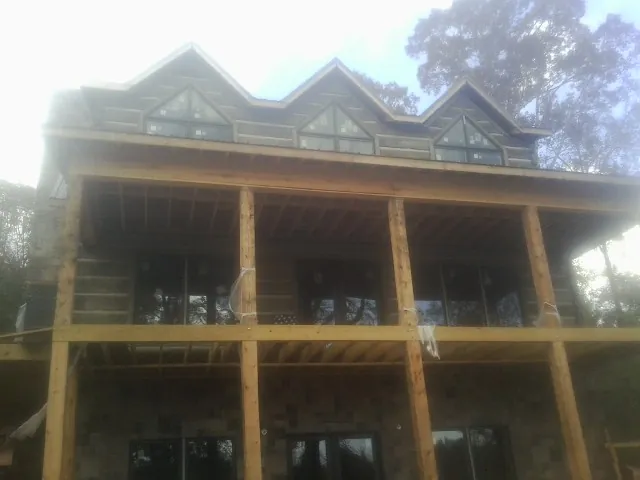 Dormers and porch framing on a large log home under construction — Roof Coating work by our crew in Wendell